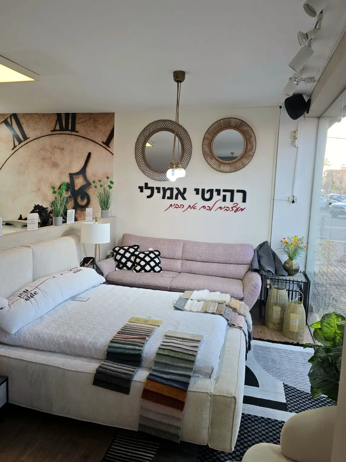 מיטה זוגית מרופדת מסודרת במצעים בחלל התצוגה של החנות