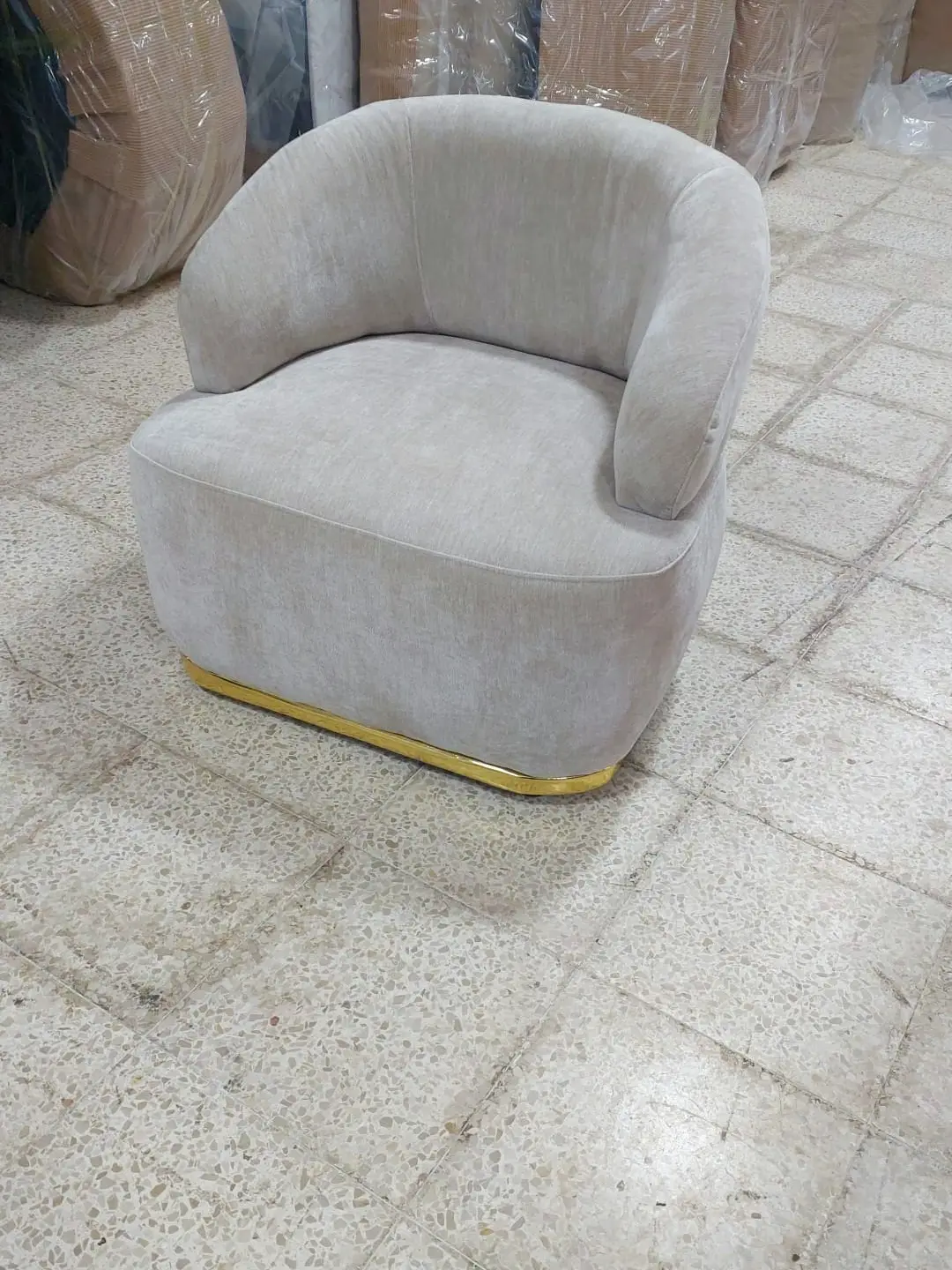 כורסה מעוגלת בגוון קרם עם פס זהב בבסיס