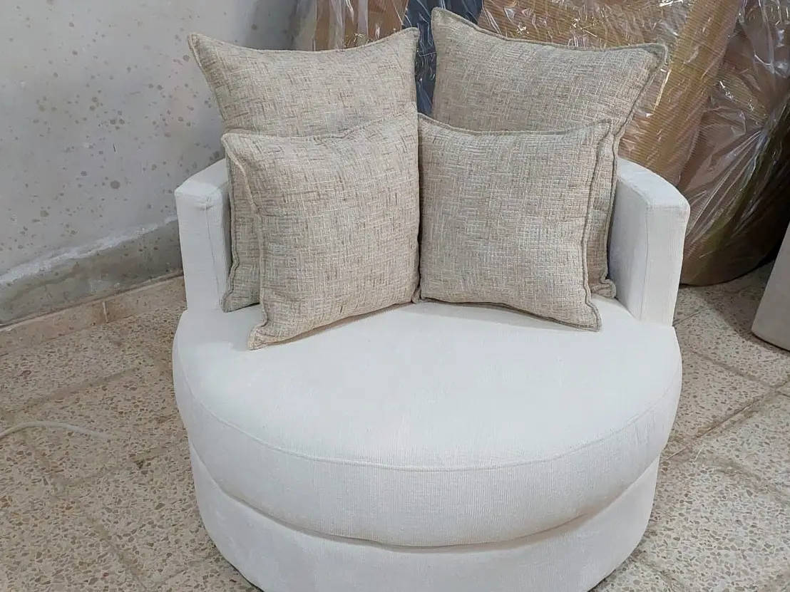 כורסה עגולה ורחבה בגוון קרם עם שתי כריות נוי