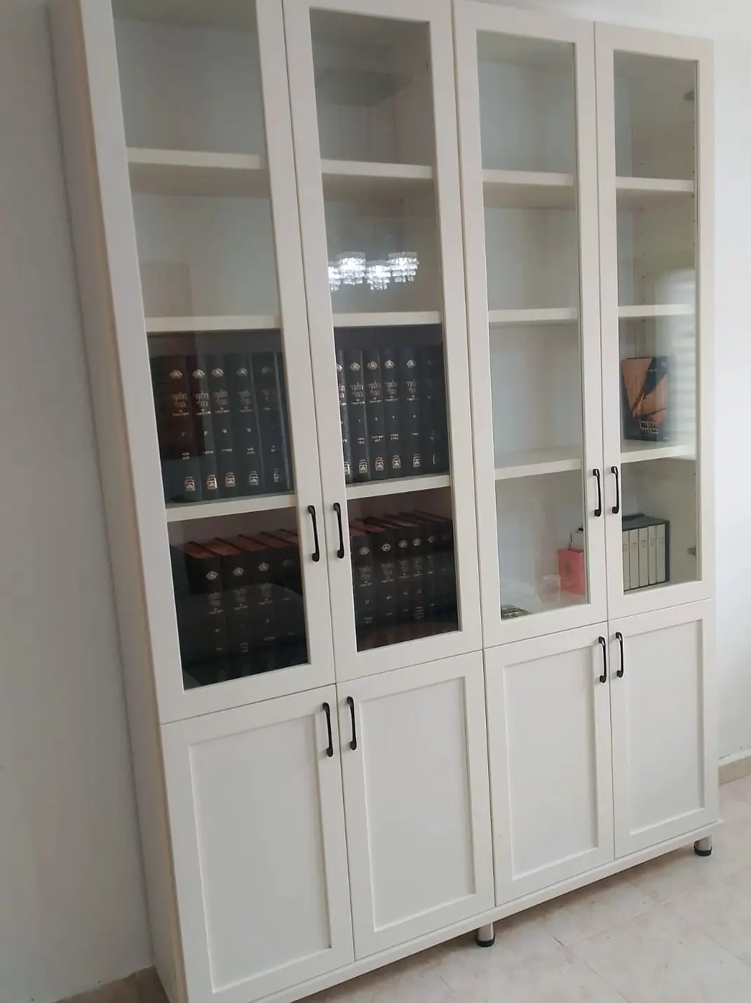 ספרייה בגוון שמנת עם דלתות זכוכית בחלק העליון ודלתות מלאות בתחתית