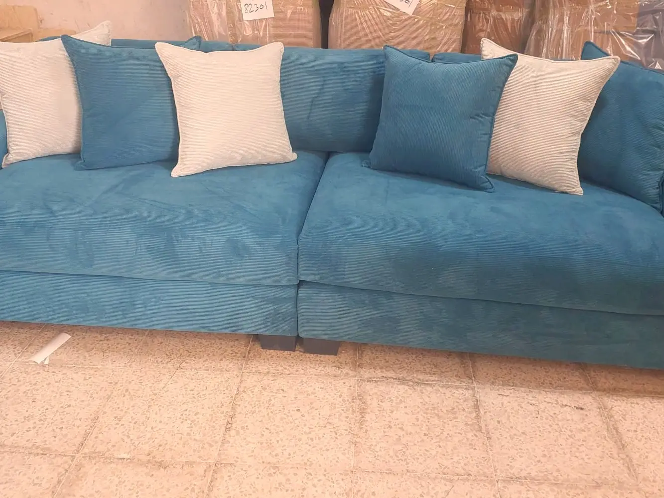 ספה רחבה בגוון כחול ים עם כריות נוי לבנות